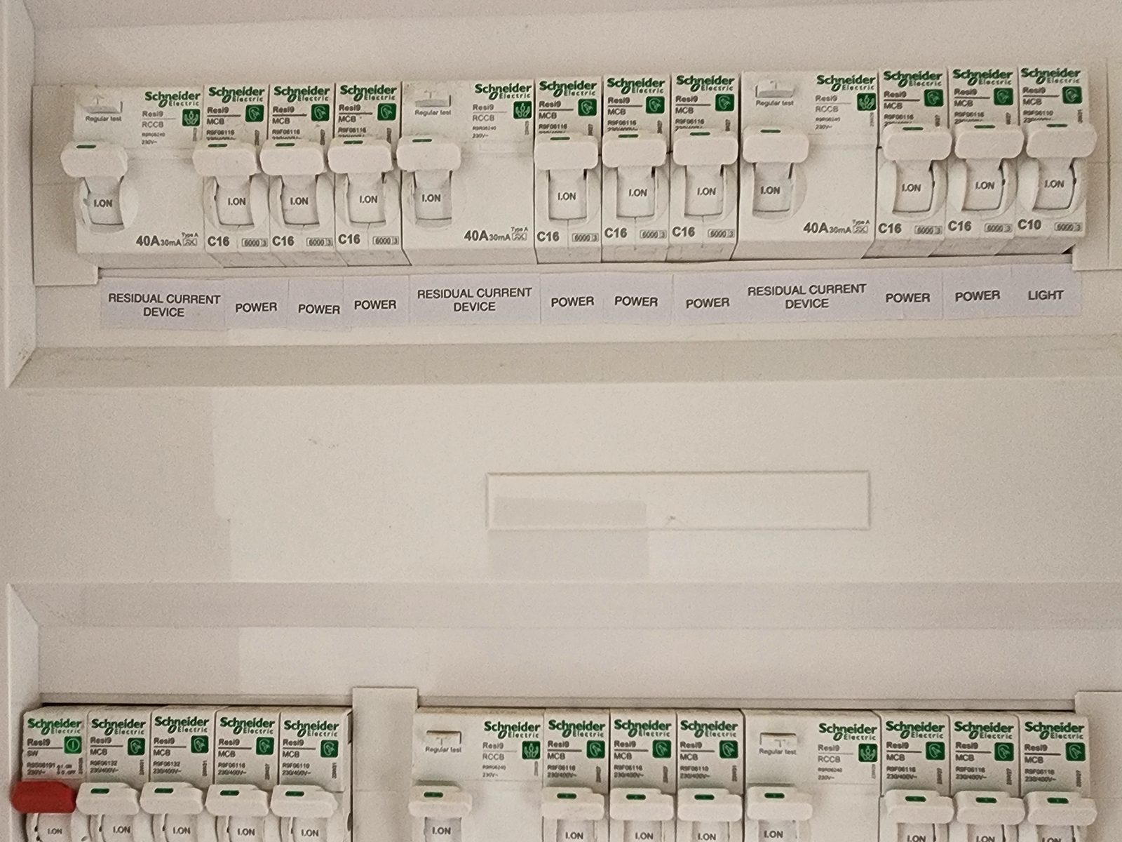 An open switchboard with two rows of Schneider Electric breakers and safety switches, each circuit labelled.