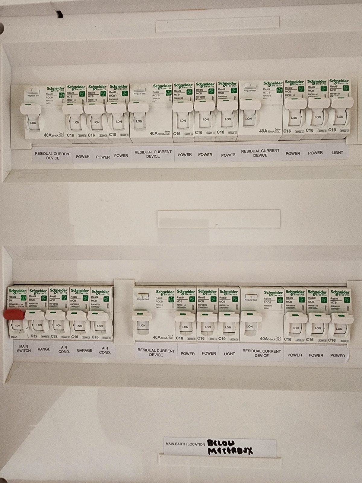 An open switchboard with two rows of Schneider Electric breakers and safety switches, each circuit labelled.