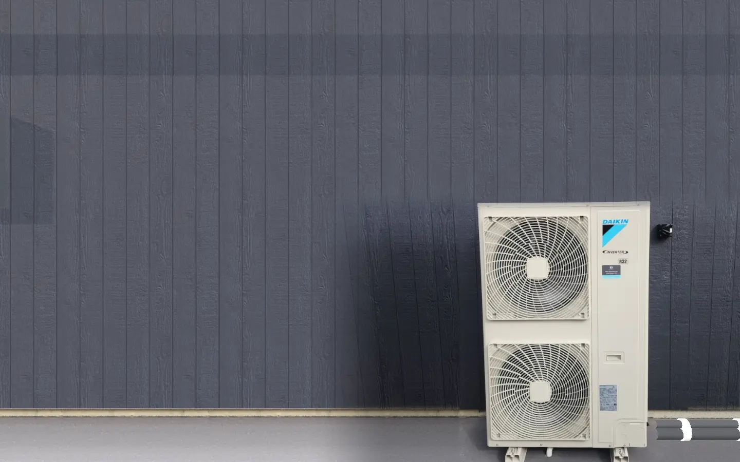 A Daikin Inverter outdoor heat pump unit against dark board-and-batten cladding, with a Steel Electrical and Heat Pumps service sticker on the casing